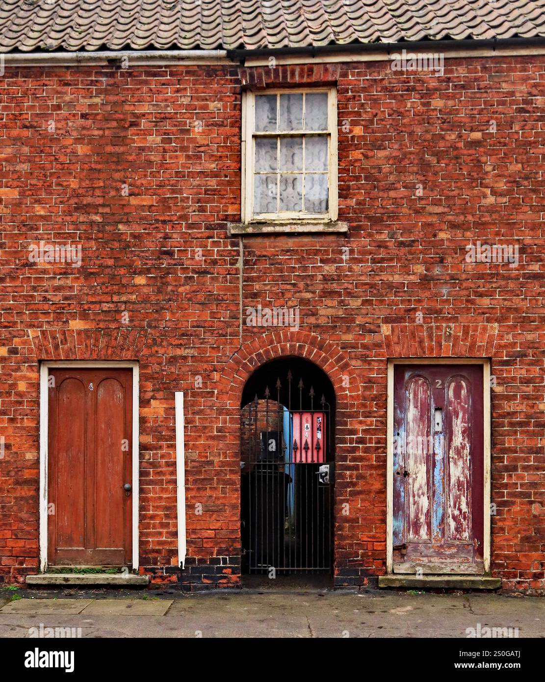 Die Farbe an den Vordertüren dieser Straßenhütten sieht aus, als ob sie im Dorf Wainfleece All Saints in Lincolnshire getragen wurden Stockfoto