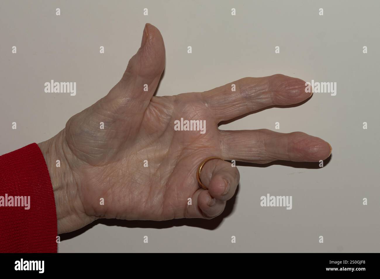 Nahaufnahme der Hand einer älteren Frau, die die Zahl drei zeigt, wobei die Hautstruktur der Alten betont und ein einfacher Hintergrund dargestellt wird Stockfoto