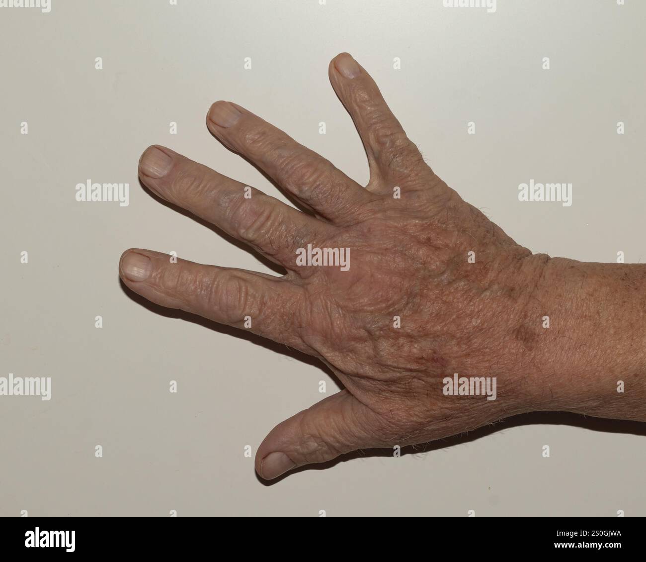 Nahaufnahme einer älteren Hand, die vollständig geöffnet ist und alle fünf Finger ausgestreckt sind, vor einem einfachen Hintergrund. Diese Geste stellt in der Regel die Zahl dar Stockfoto