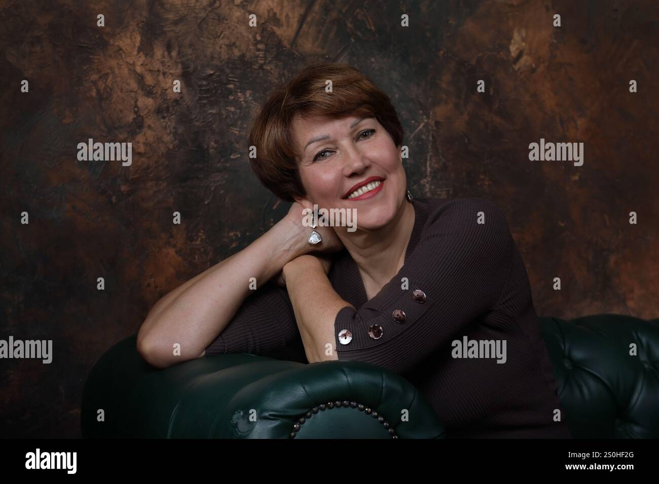 Porträt einer gut gelaunten Frau mittleren Alters auf braunem Hintergrund Stockfoto