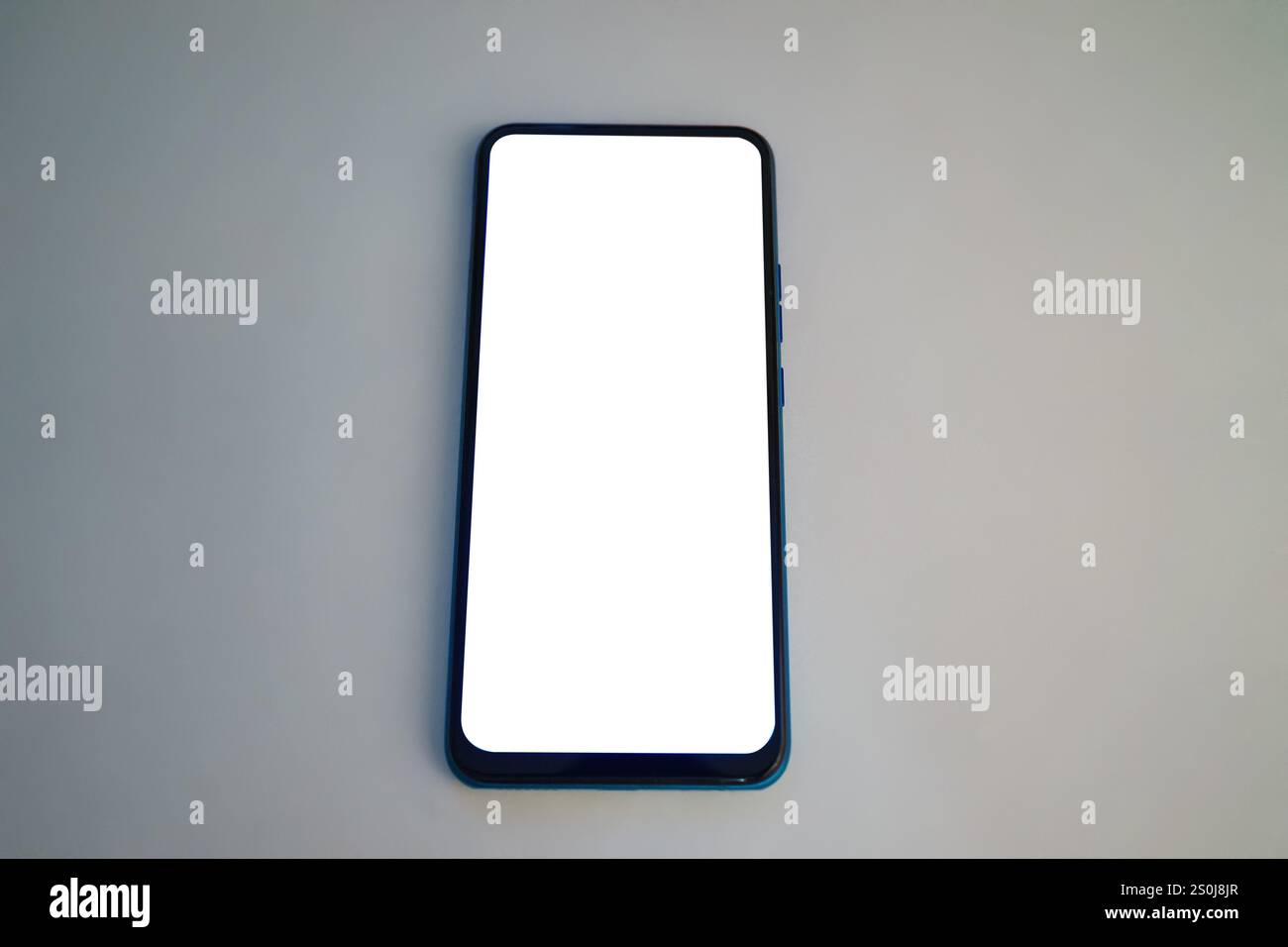 Ein leeres Smartphone befindet sich auf einer glatten Oberfläche, die durch sanfte Beleuchtung beleuchtet wird. Der Bildschirm ist leer und bietet einen minimalistischen Look. Diese Einstellung schlägt vor Stockfoto
