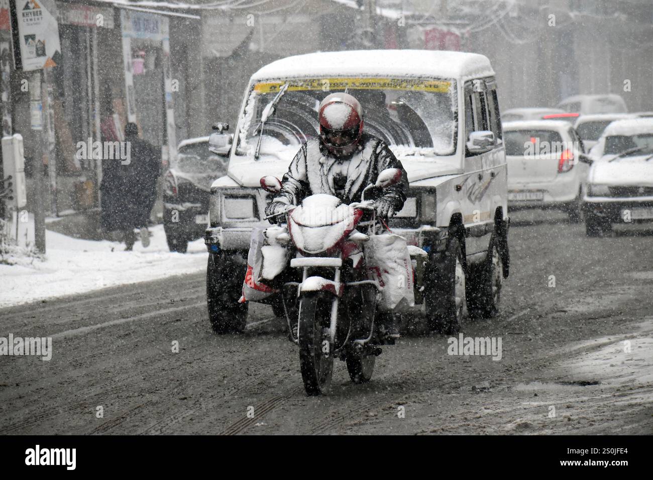 Srinagar, Indien. Dezember 2024. Ein Mann, der am 27. Dezember 2024 in Pulwama, Kaschmir, auf einer rutschigen Straße mit dem Motorrad fährt. (Foto: Danish Showkat/SIPA USA) Credit: SIPA USA/Alamy Live News Stockfoto