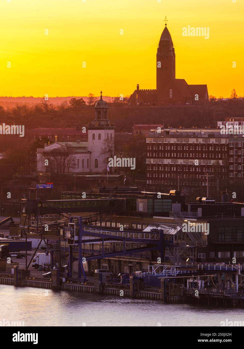Bei Sonnenaufgang erwacht Göteborg mit warmen Farbtönen, die die Skyline und die Uferpromenade beleuchten. Die Silhouetten von Kirchen und modernen Bauten schaffen eine Stockfoto