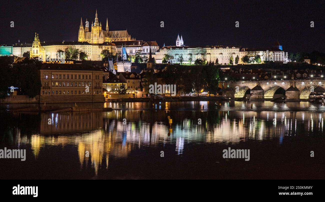 Ein atemberaubender nächtlicher Blick auf die Prager Burg, beleuchtet gegen den Nachthimmel, reflektiert in der Moldau. Die Szene umfasst die Karlsbrücke und su Stockfoto