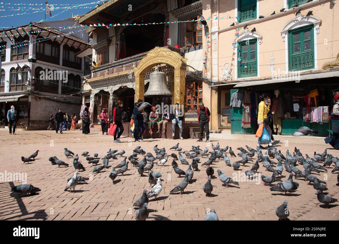 Kathmandu, Nepal, 8. März 2020: Tauben fliegen über Einheimische und Touristen, die um die alte Glocke auf dem Durbar-Platz in kathmandu Nepal spazieren Stockfoto