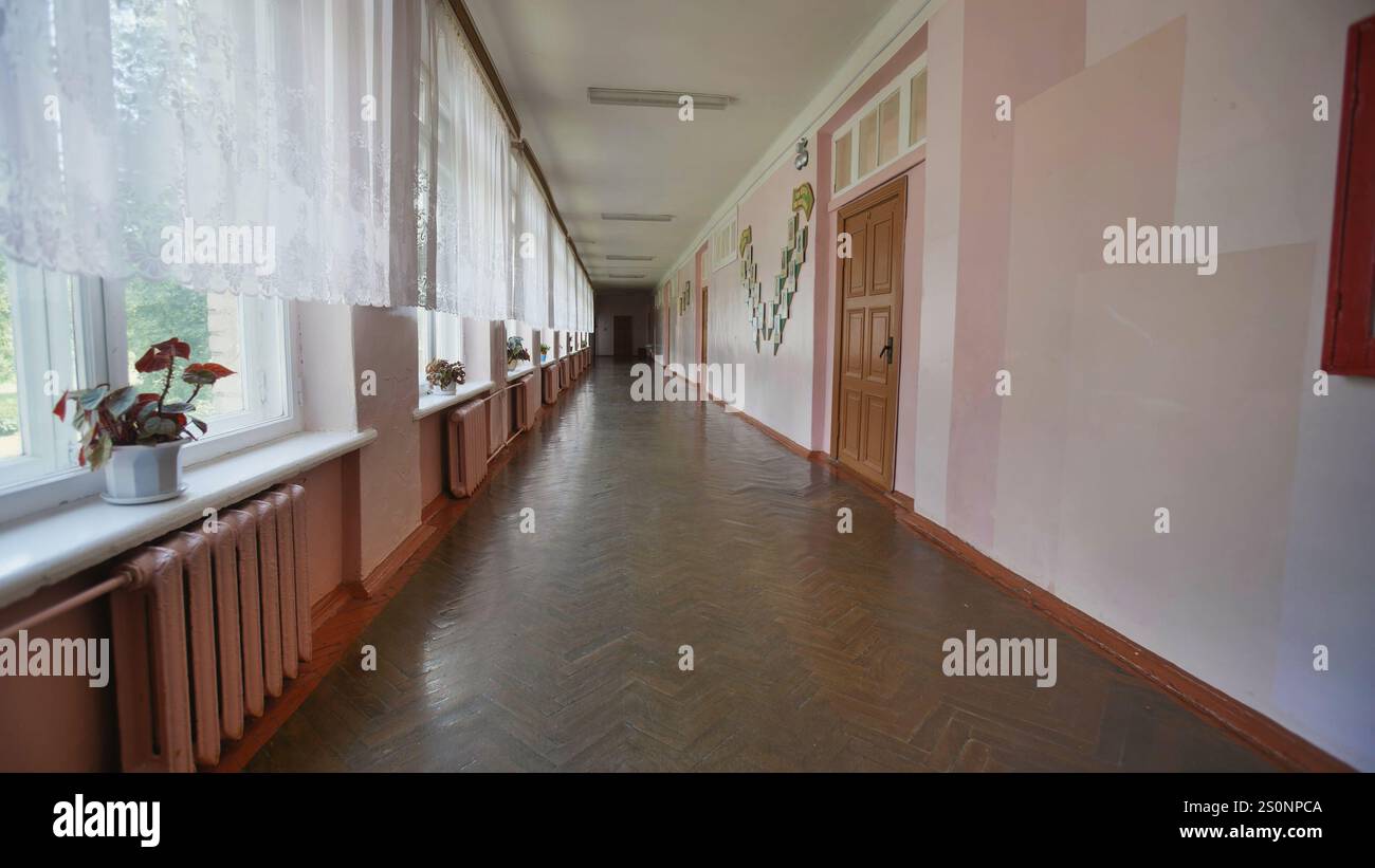 Sonnenlicht, das durch Fenster in einem leeren Schulflur leuchtet, ruft Nostalgie am letzten Schultag hervor Stockfoto