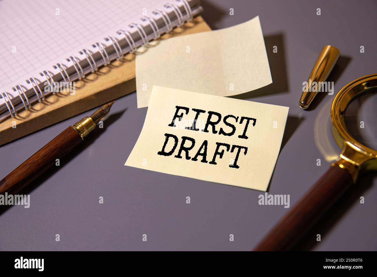 Schwarzes Notizbuch, Stift auf rotem Kopierraum-Hintergrund, gelbe Haftnotiz mit Text ERSTER ENTWURF, bezieht sich auf Autor, der die erste Version des Buches beendet, manuscr Stockfoto