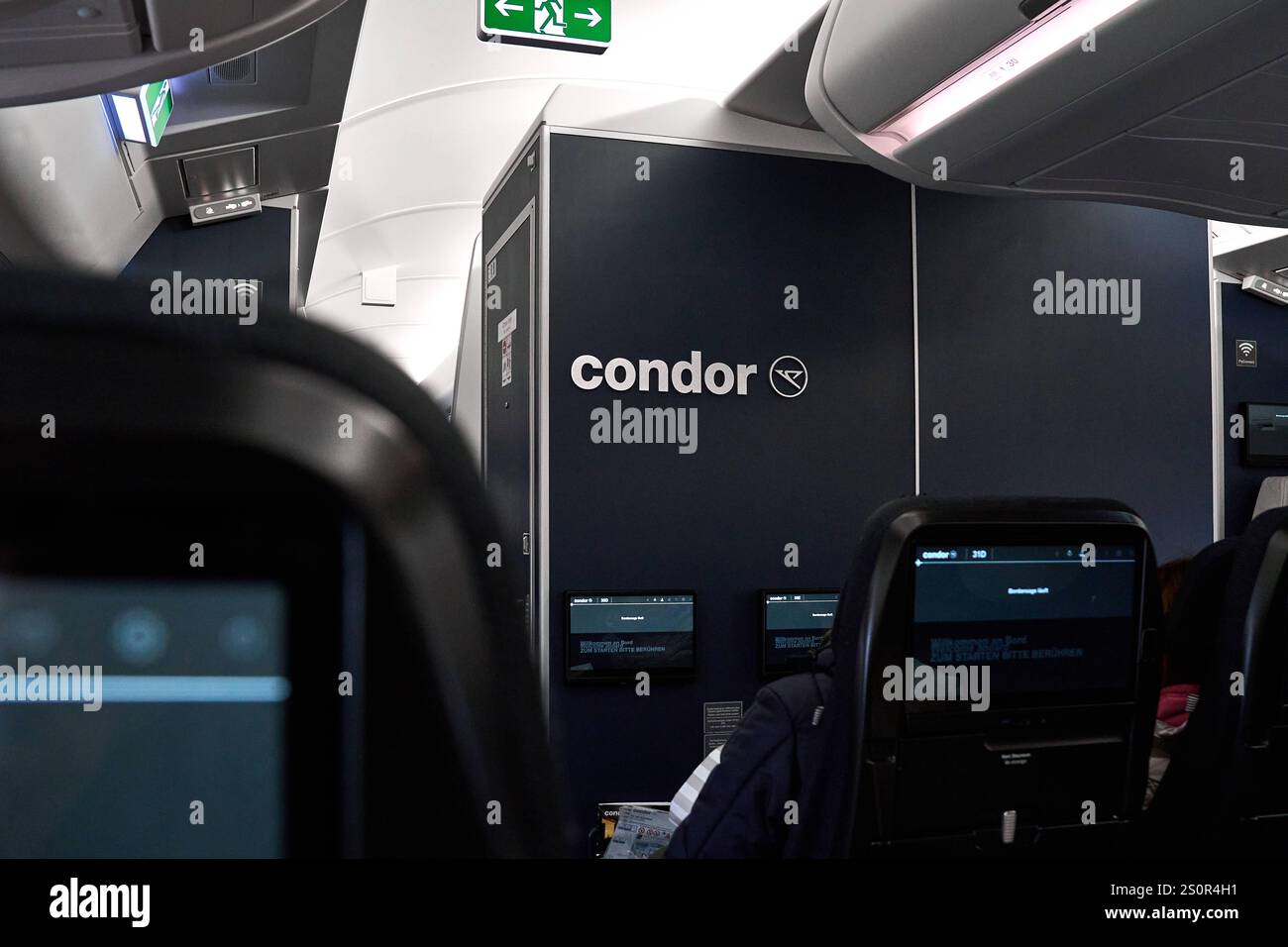 Deutschland - 28. Dezember 2024: Blick in den Innenraum eines Condor Airbus A330neo-Flugzeugs mit schwarzen Sitzen, Bildschirmen und einer Wand mit Condor-Logo im Hintergrund *** Blick in den Innenraum eines Condor Airbus A330neo-Flugzeuge mit schwarzen Sitzen, Bildschirmen und einer Wand mit Condor-Logo im Hintergrund Stockfoto