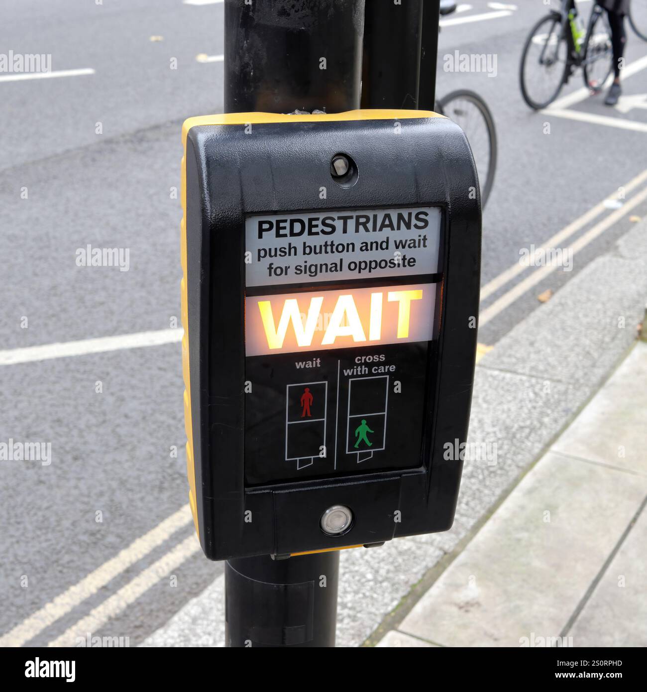 Taste für die Fußgängerbeleuchtung am Quersteg zur sicheren Straßenüberquerung in London, die das Warten-Signal anzeigt Stockfoto
