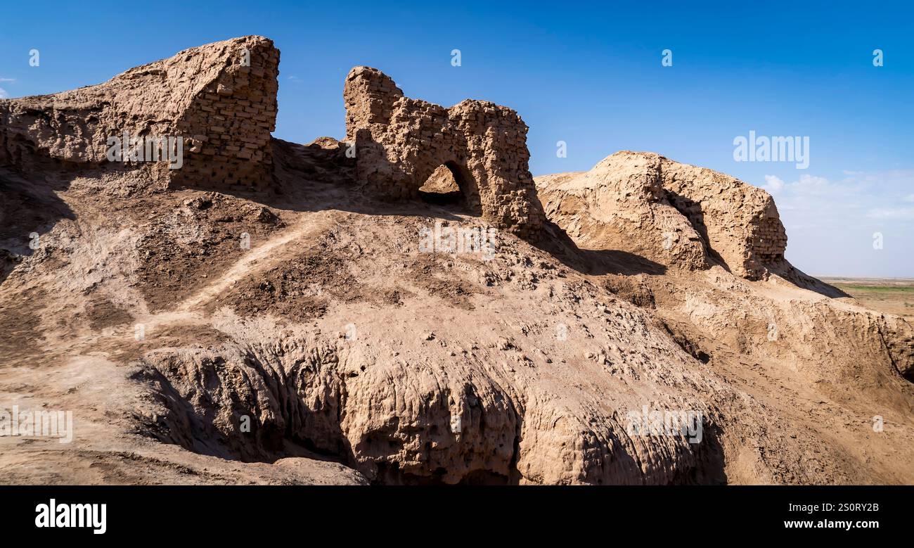 Alte Ruinen einer Festung oder Burg auf felsigem Gelände unter klarem blauen Himmel. Das Gebäude zeigt verwitterte Steinmauern und -Bögen, umgeben von d Stockfoto