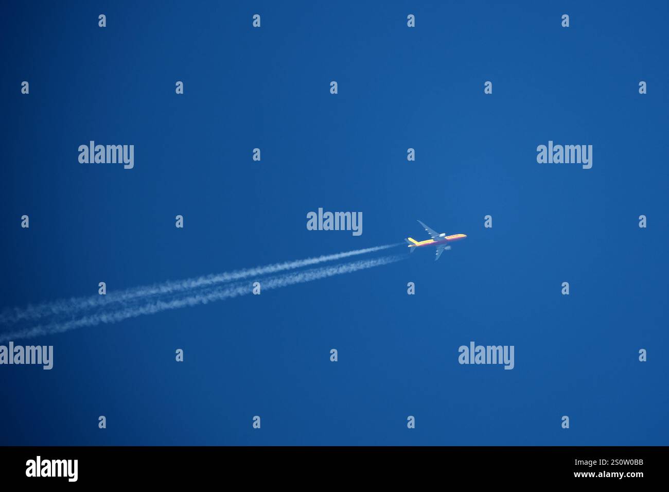 Flugzeug am blauen Himmel. DHL Cargo. Flugzeug am blauen Himmel mit Kondensstreifen. Stockfoto