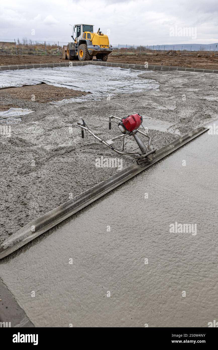 Bauarbeiter verwenden Kraftestriche zum Glätten der Betonoberfläche auf der Baustelle Stockfoto