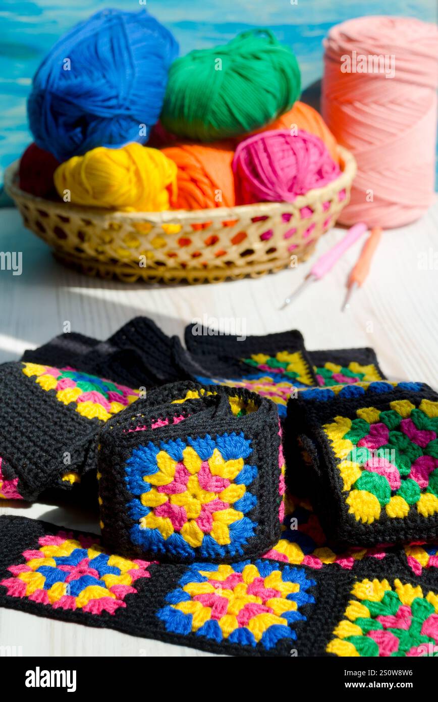 Handgestrickte Zickzack-Ornamente und Stränge aus mehrfarbigen Garnen. Farbenfrohe Baumwoll-Oma-Quadrat. Häkeln Sie die Textur aus der Nähe des Fotos. Stockfoto