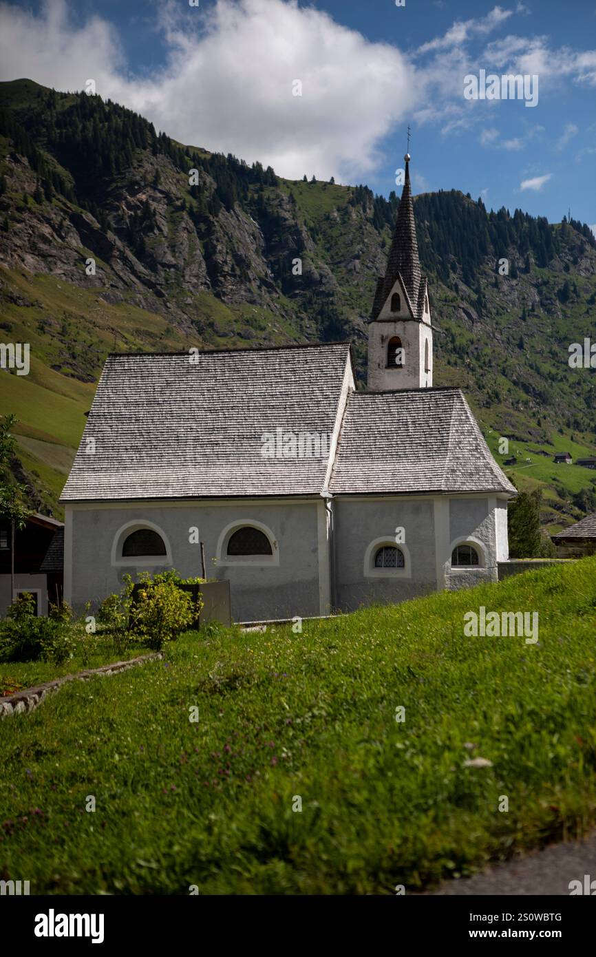 Die Pfarrkirche Mariä Himmelfahrt in Moos, in einer malerischen Alpenlandschaft an einem sonnigen Sommertag mit klarem blauem Himmel. Stockfoto
