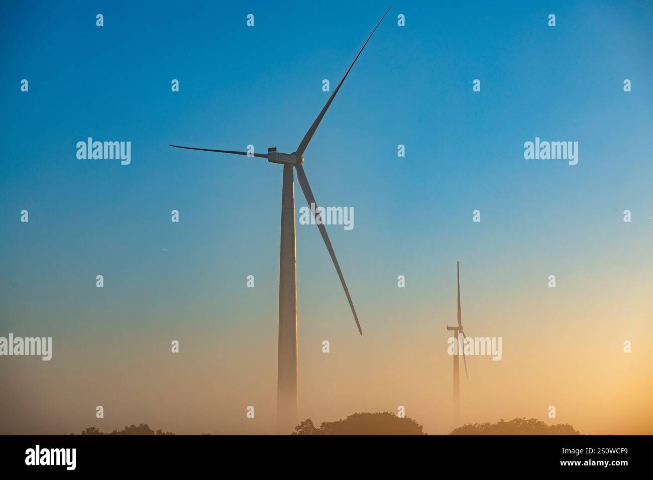 Zwei Windturbinen in den Feldern von La Mancha, Spanien, bei einem farbenfrohen Sonnenaufgang Stockfoto