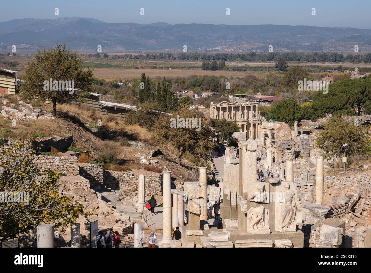 Türkei, Turkiye. Römische Ruinen in Ephesus, Blick auf die Celsus-Bibliothek, mit einem alten Hafen im Hintergrund (jetzt verschlungen). Stockfoto
