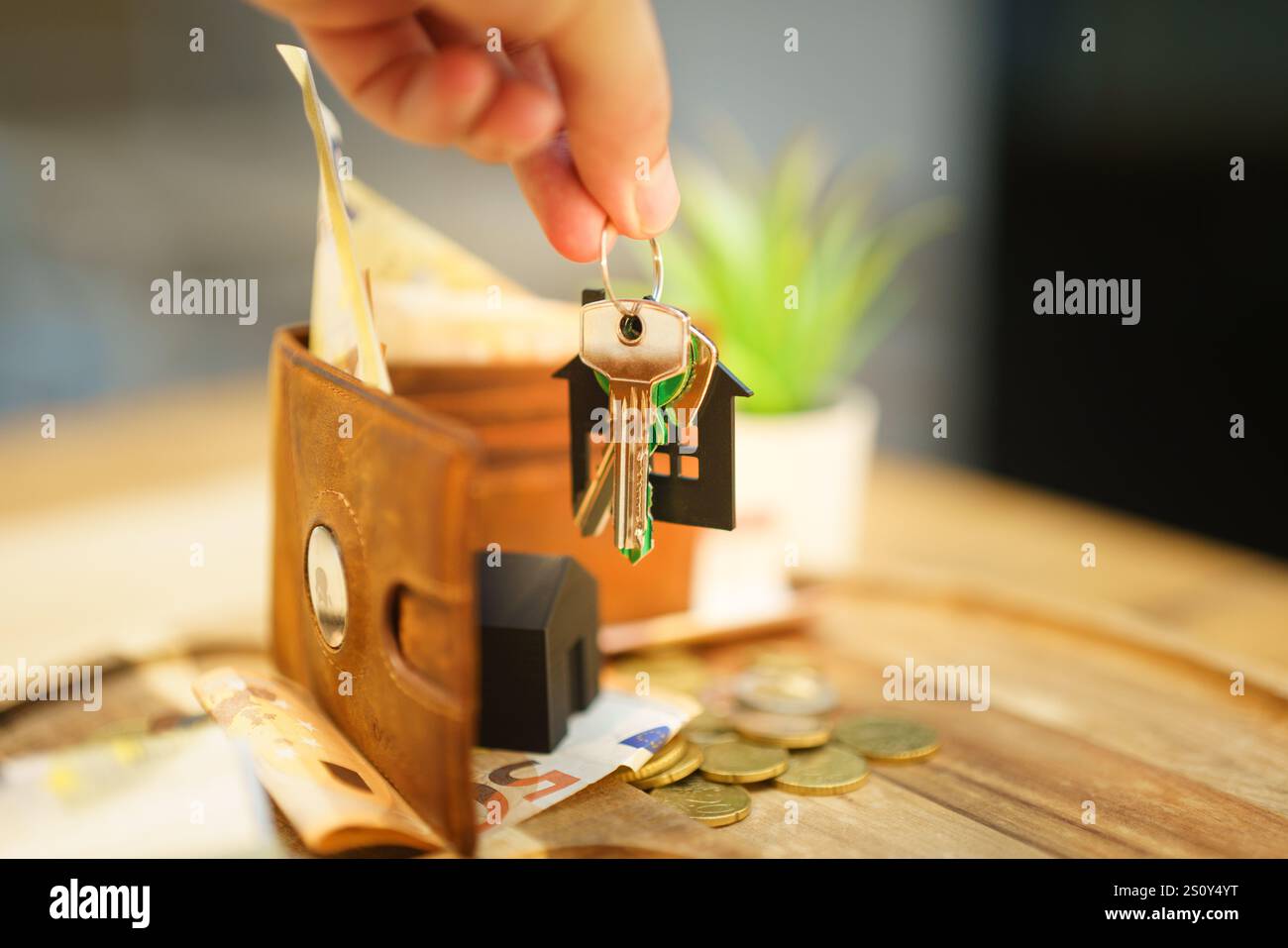 Handgriff Türschlüssel neue Haus Haushalt Ausgaben Rechnungen Wallet Woodenn Tisch grün Pflanze Immobilien Markt Stockfoto