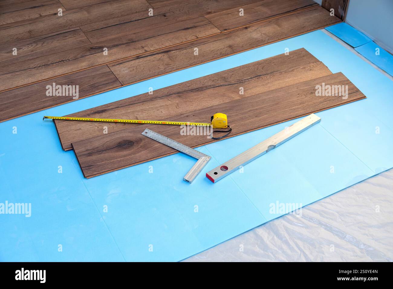 Aufgerollter Laminatboden mit Maßband und Ebene Stockfoto