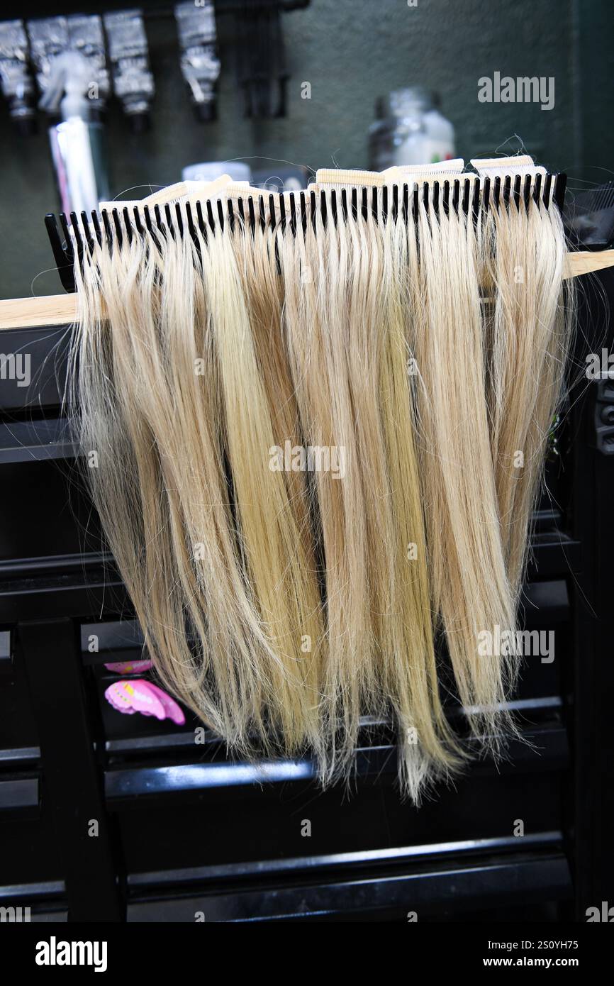 Blonde Haarverlängerungen ordentlich auf einem Regal in einem Salon angeordnet. Stockfoto