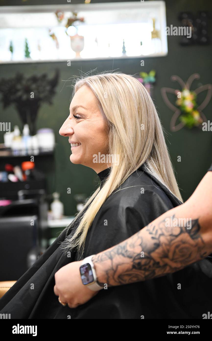 Kunde mit schlanken blonden Haaren, die nach einer Salonsitzung lächeln, Stall Stockfoto