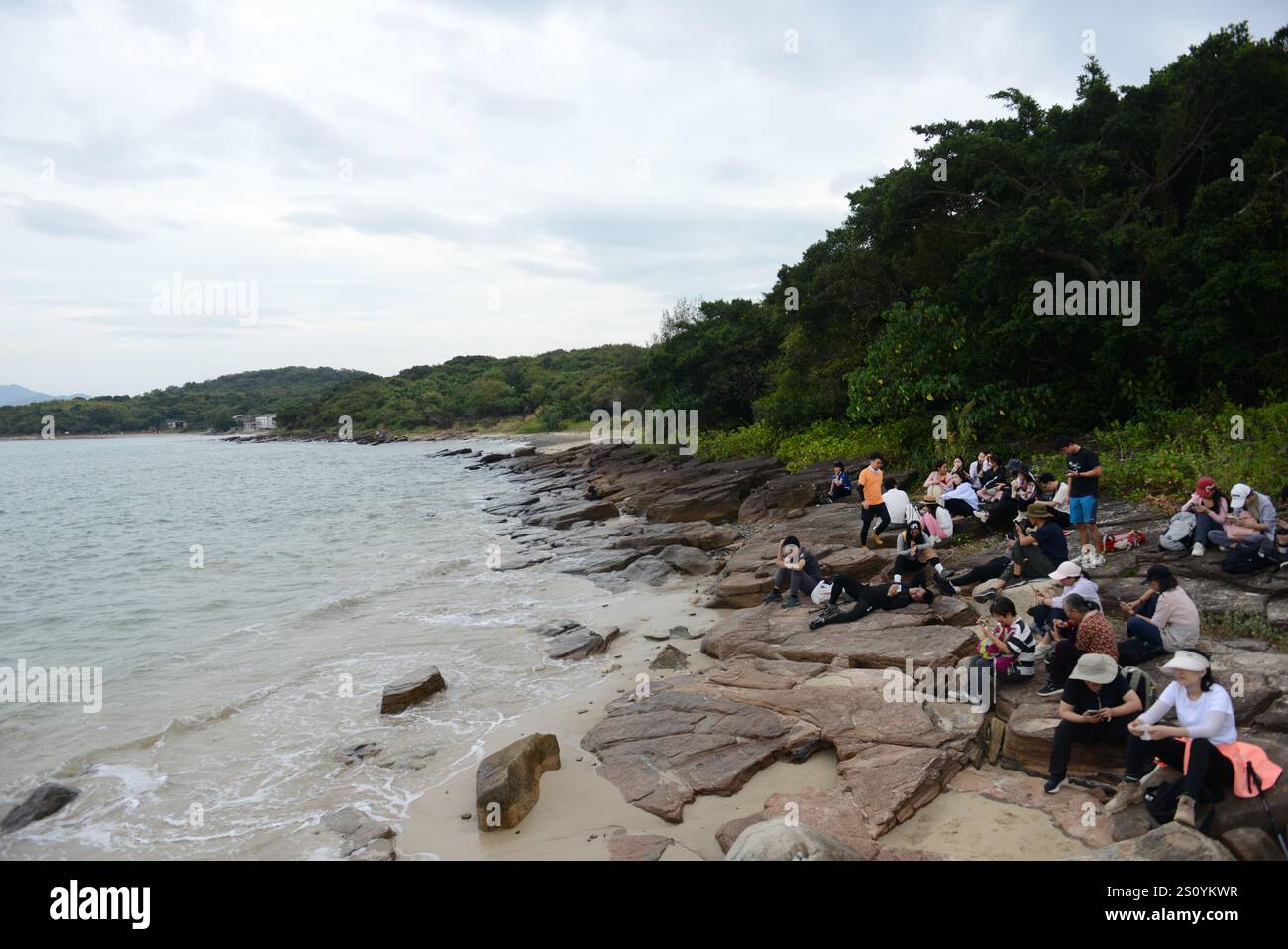 Tourist sitzt am felsigen Ufer der Insel Tung Ping Chau in Hongkong. Stockfoto