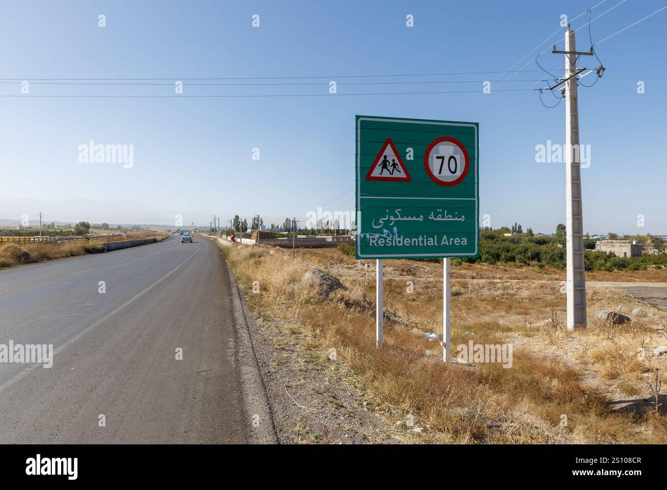 Ein Verkehrsschild warnt die Fahrer vor einem Wohngebiet entlang einer Landstraße im Iran. Die Geschwindigkeitsbegrenzung ist auf 70 Kilometer pro Stunde festgelegt. Stockfoto