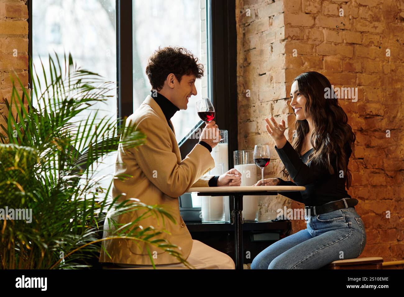 Ein Paar teilt sich Lachen und Wein und feiert ihre Liebe in einer intimen Restaurantatmosphäre. Stockfoto