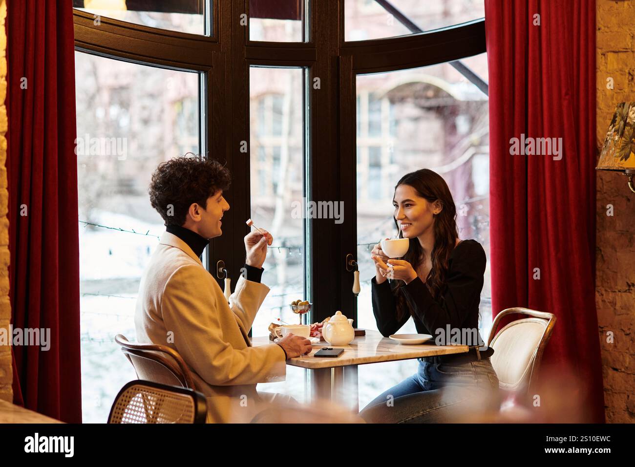 Ein junges Paar genießt eine romantische Mahlzeit, lächelt und teilt intime Gespräche miteinander. Stockfoto