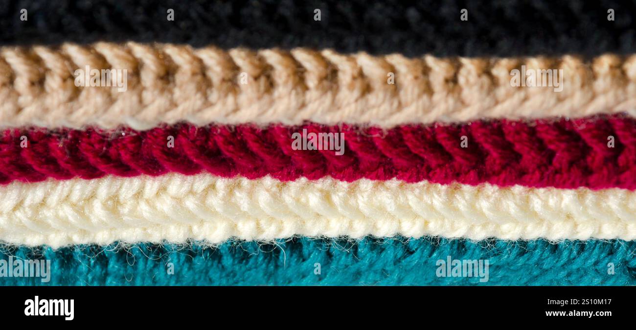 Die Textur von Wollgemisch-Garnproben. Nahaufnahme mehrfarbiger Häkelmuster. Stockfoto