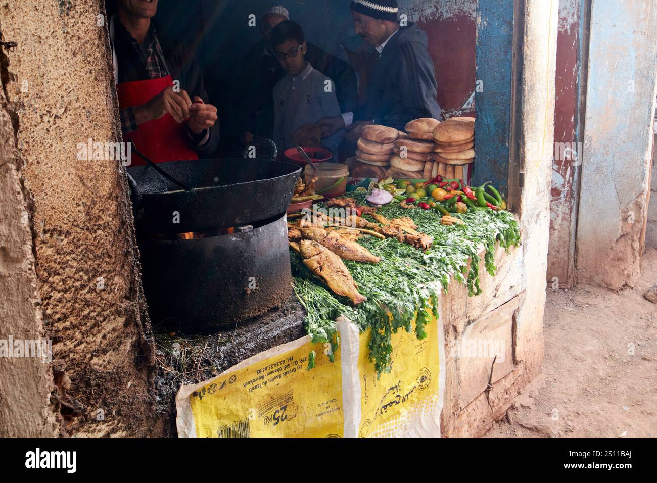 Frischer frittierter Fisch in einer großen Pfanne Öl über einem Holzkohlefeuer an einem Stand am traditionellen berbermarkt amazigh Markt asni marokko gebraten Stockfoto