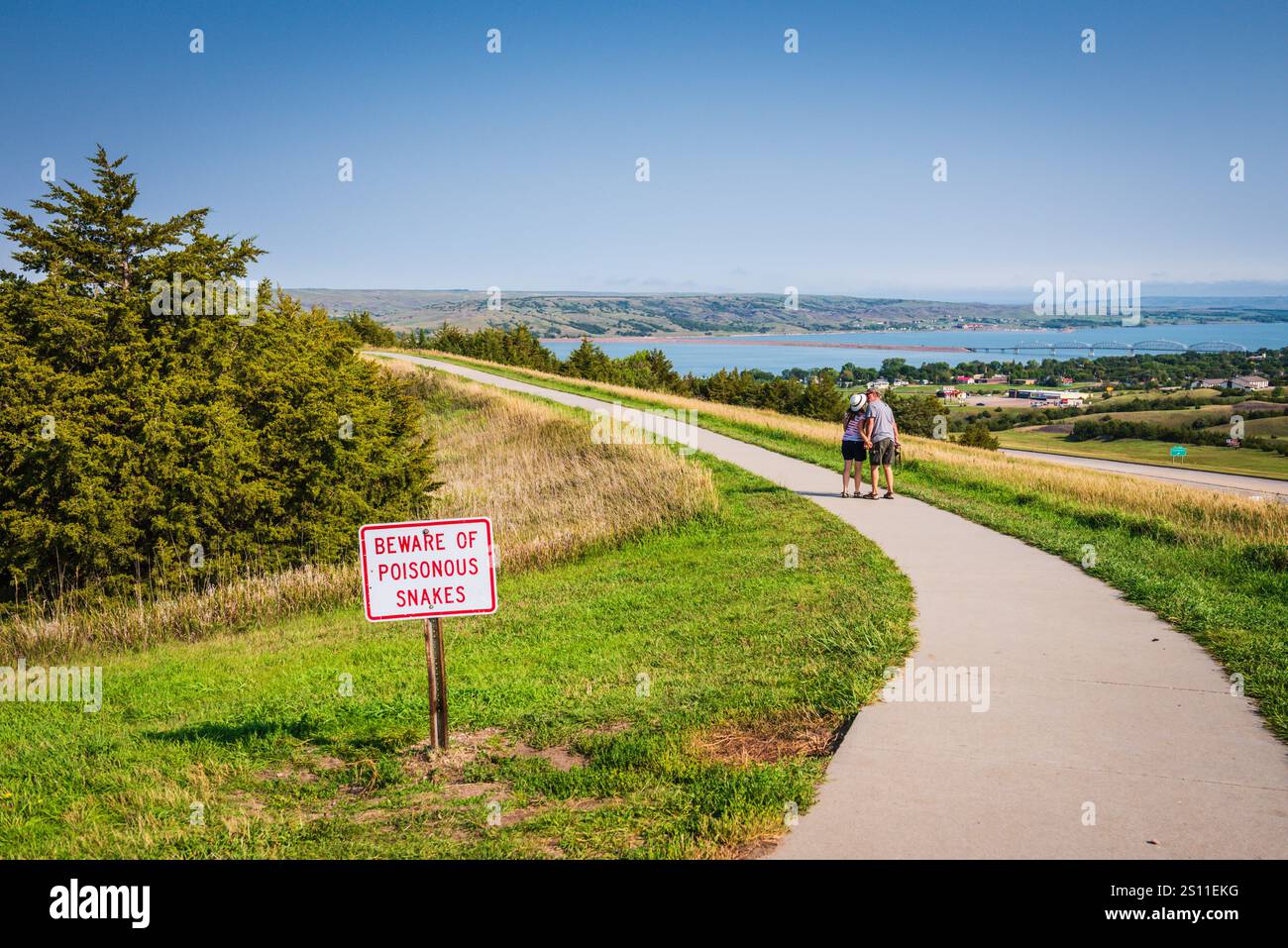 Chamberlain SD USA - 26. August 2017: Paare küssen sich auf einem Pfad mit Blick auf den Missouri River, vorbei an einem Schild mit der Aufschrift „Vorsicht vor giftigen Schlangen“. Stockfoto