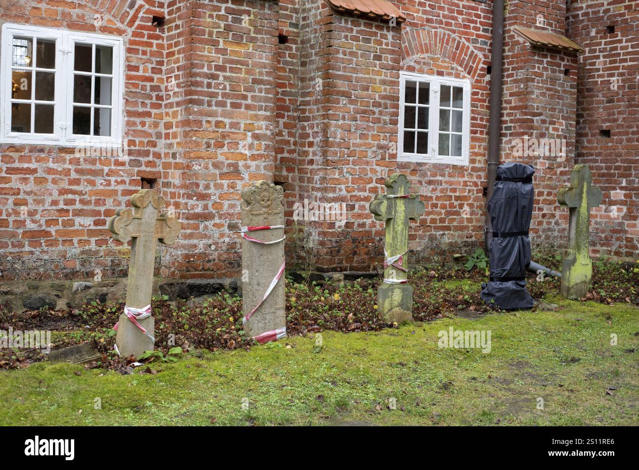 Alte Grabsteine vor einer roten Backsteinmauer mit kirchlichen Fenstern im Hintergrund, Seemannskirche Prerow, Prerow, Mecklenburg-Vorpommern, Ger Stockfoto