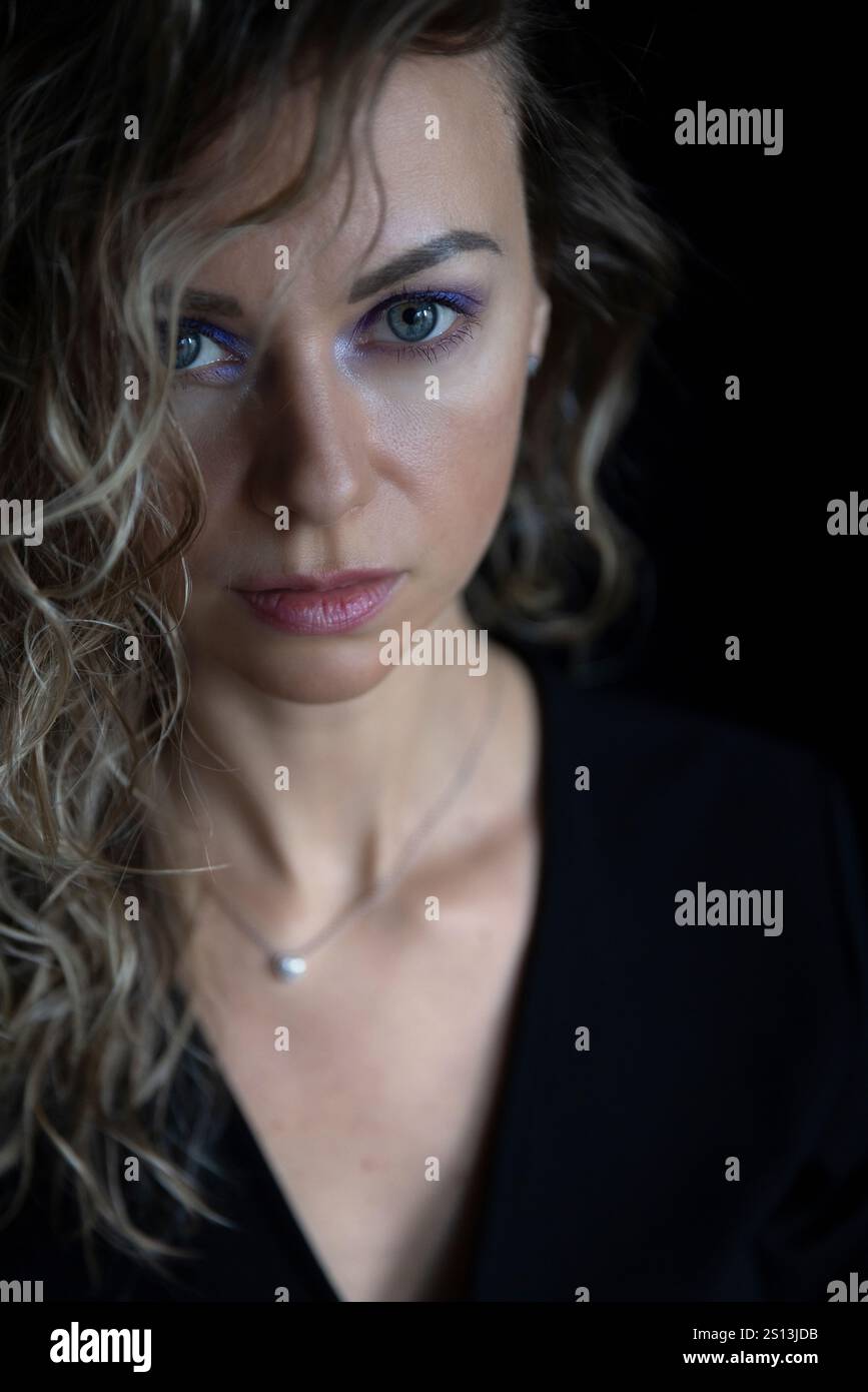 Zarte junge blonde Frau mit großen blauen Augen, die direkt in die Kamera blickt. Stockfoto