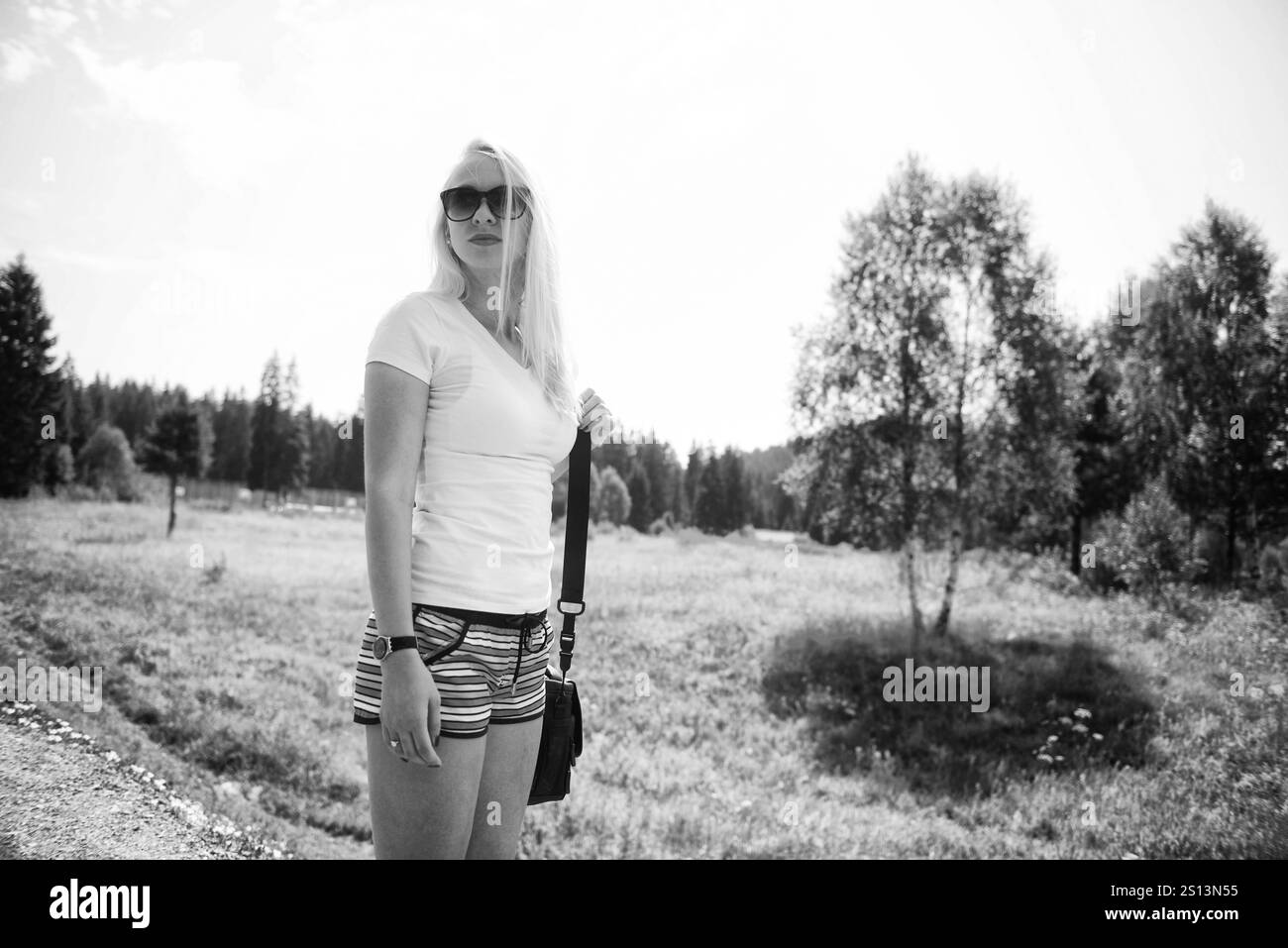 Frau, die auf Einer ruhigen Straße läuft, mit Sonnenbrille und Einer Tasche auf der Schulter Stockfoto