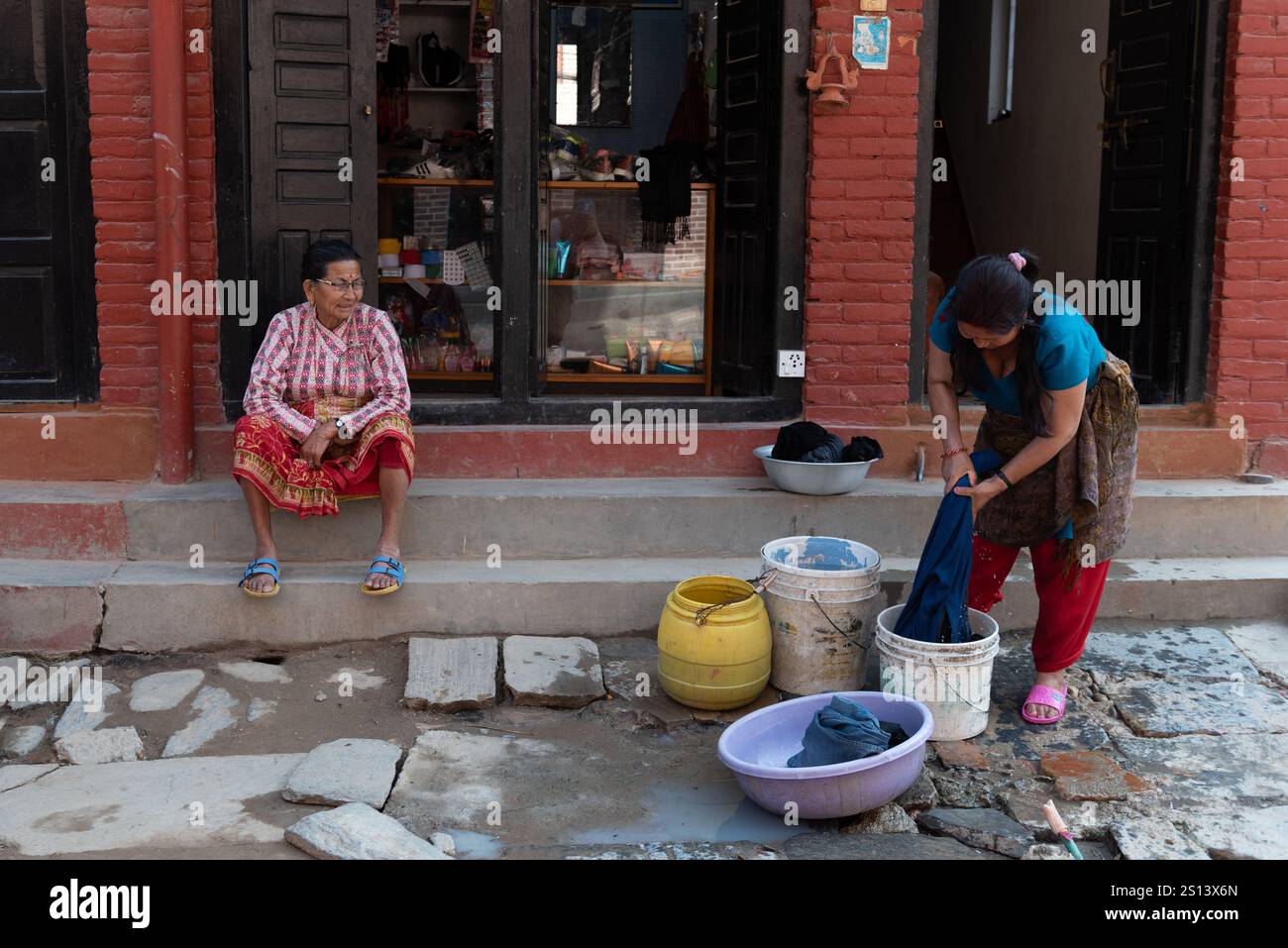 Kathmandu, nepal, 10. März 2020: Nepalesische Frauen waschen vor einem Geschäft in kathmandu. Frau wäscht Kleidung und plaudert mit kathmandu, nepal Stockfoto