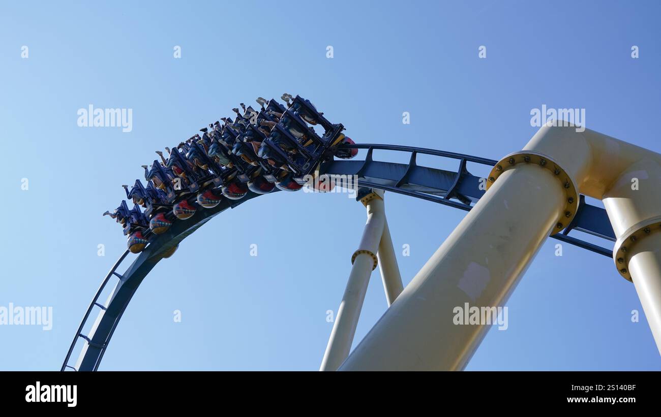 Auf der intensiven umgedrehten Achterbahn „Ozlris“ des Herstellers „B&M“ im Freizeitpark „Asterix“ fahren die Menschen durch eine Inversion Stockfoto