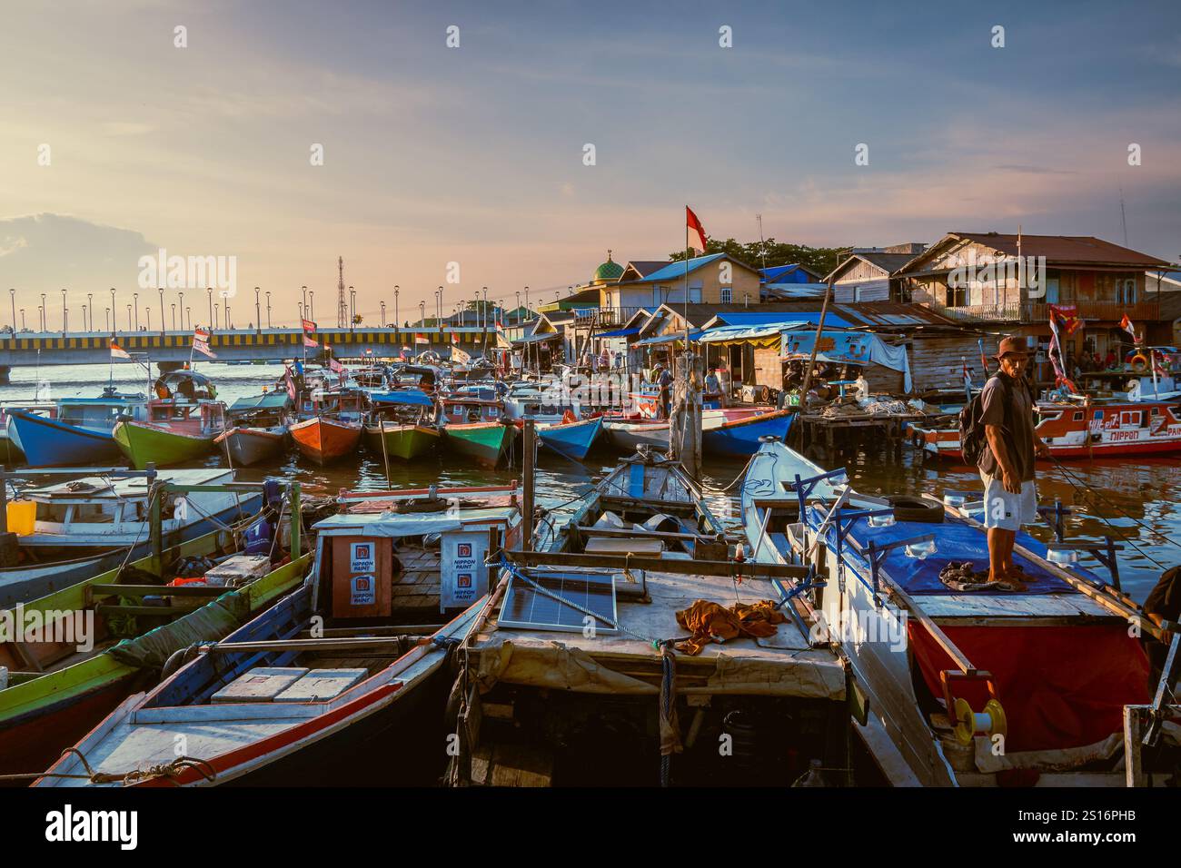 Balikpapan, Ost-Borneo, Indonesien. Eine Reihe von Booten ist in einem Hafen angedockt, mit einer roten und weißen Flagge auf einem davon Stockfoto