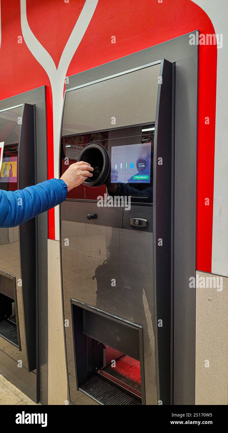 Nahaufnahme der Männerhand, die Plastikflaschen in die automatische Recyclingmaschine im Supermarkt Kaufland bringt. So sparen Sie Geld. April 2024. Uberling Stockfoto