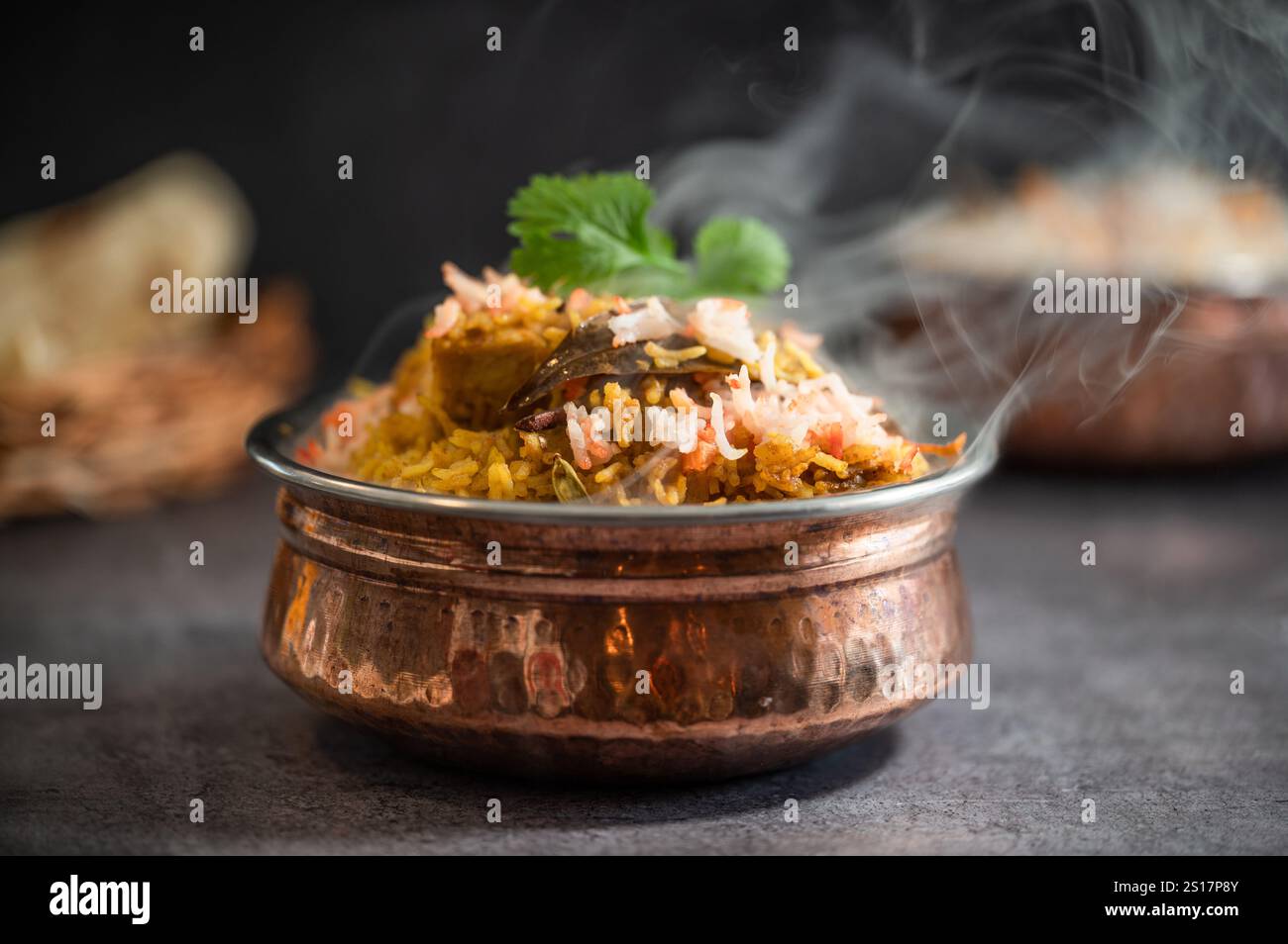 Rauchig scharfer indischer Biryani-Pulao in goldener Schüssel mit indischem Basmati-Reisgericht mit Hühnerfleisch-Curry Ramadan Kareem, Eid. Servierschüssel aus Messing mit Weißwein Stockfoto