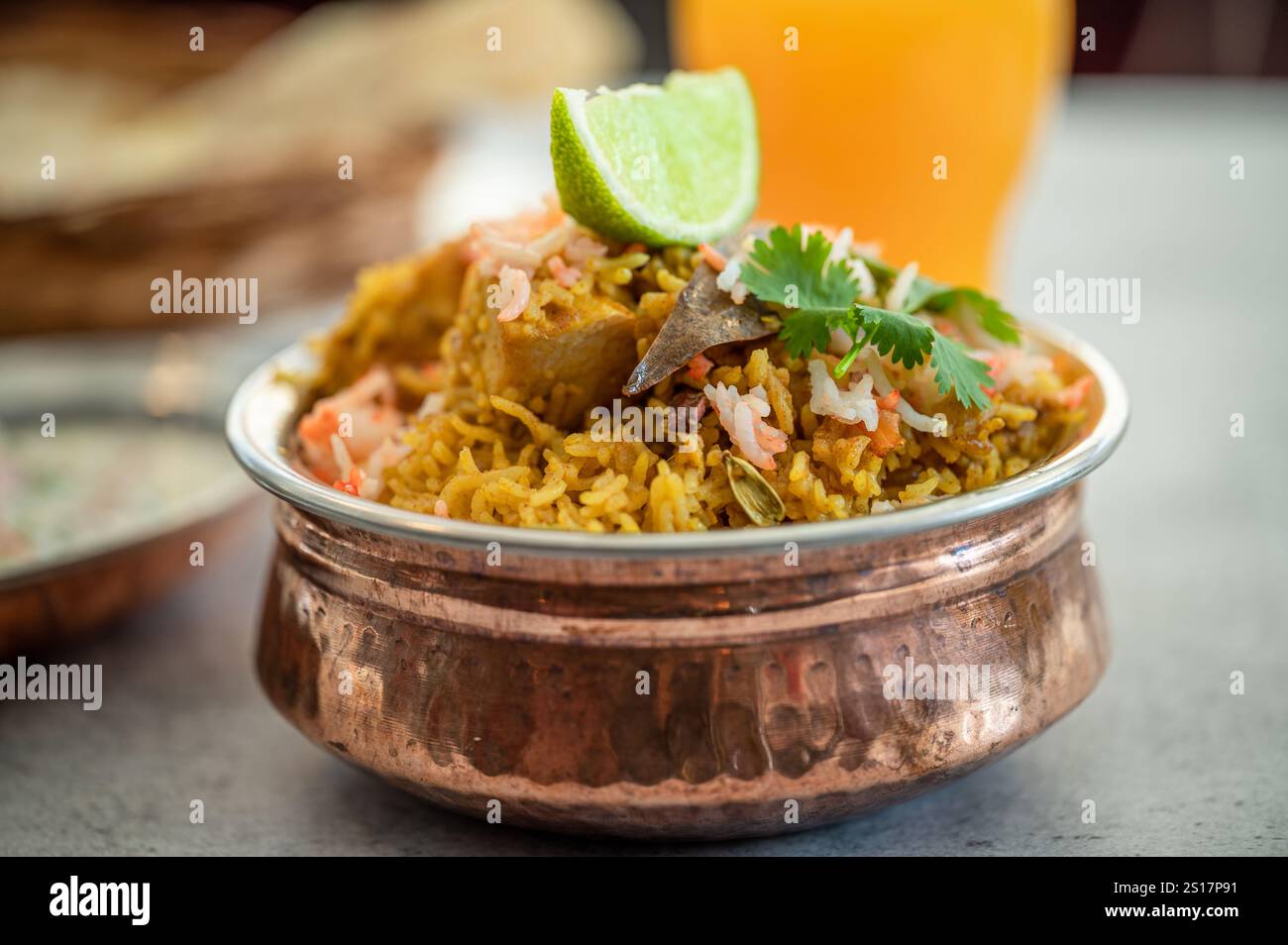 Würziger indischer Biryani-Pulao in goldener Schüssel mit indischem Basmati-Reisgericht mit Hühnerfleisch-Curry Ramadan Kareem, Eid. Servierschale aus Messing mit weißem Rücken Stockfoto