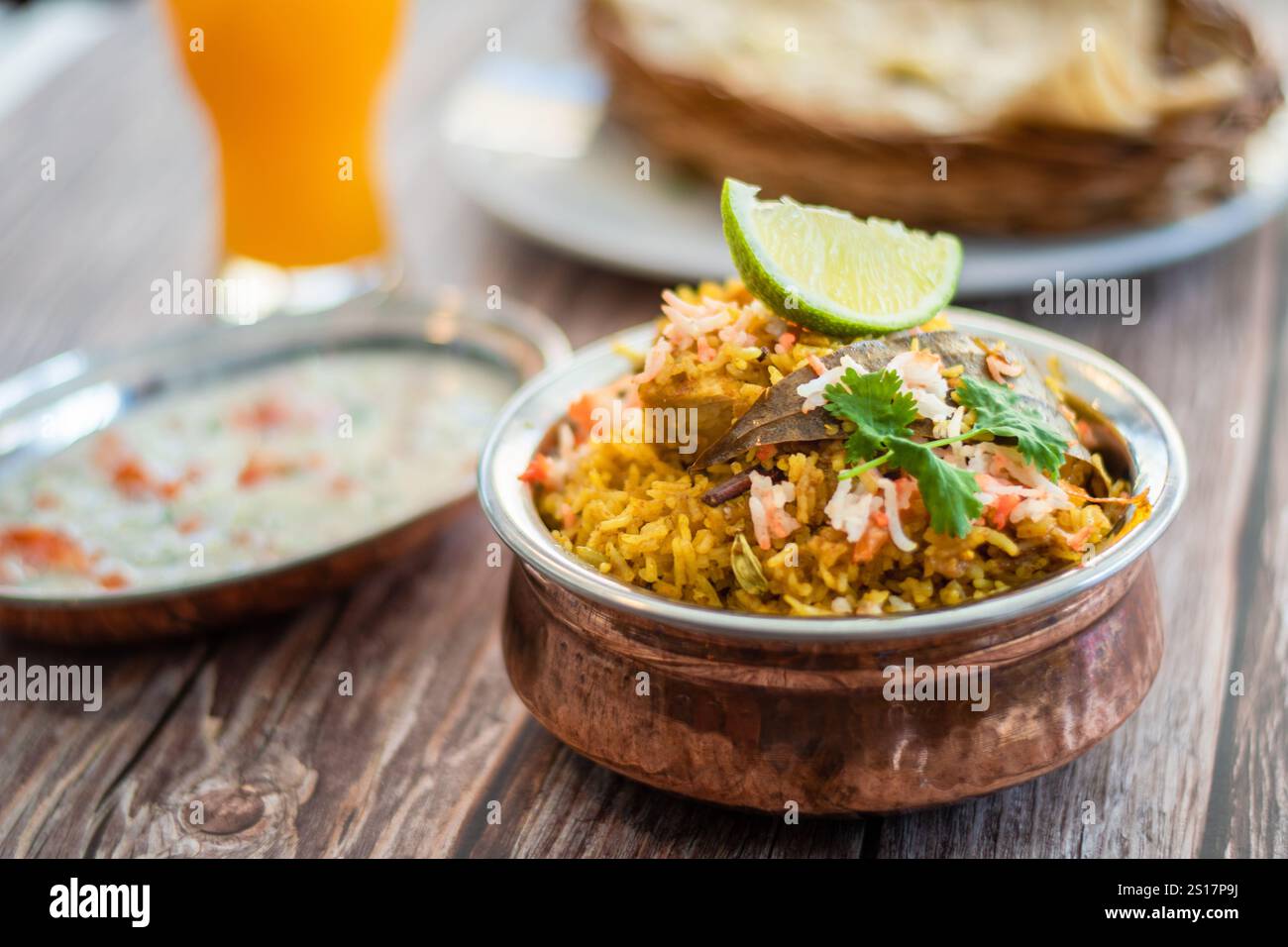 Würziger indischer Biryani-Pulao in goldener Schüssel mit indischem Basmati-Reisgericht mit Hühnerfleisch-Curry Ramadan Kareem, Eid. Servierschale aus Messing mit weißem Rücken Stockfoto