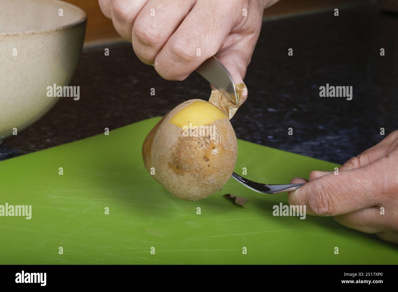 Deutsche Küche, Zubereitung von Sauerbraten mit Kartoffelpüree, Kartoffelschalen, Schälen gekochter Kartoffeln, Messer, Schneidebrett, Großmutters Küche Stockfoto