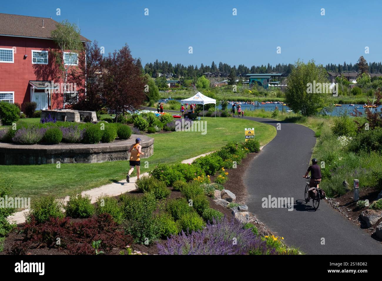 Aktive Rad- und Laufstrecken entlang des Deschutes River im Old Mill District von Bend, Oregon im Sommer Stockfoto