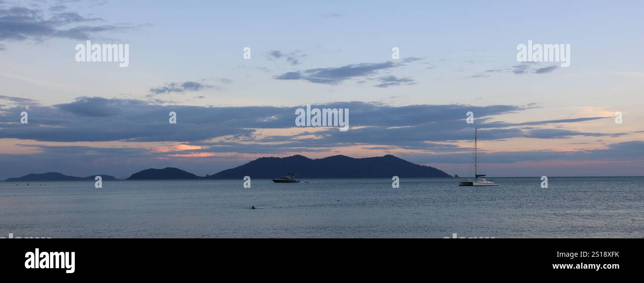Katamaran und Ko Khlum, kleine Insel bei Sonnenuntergang, Blick vom Strand Klong Kloi, Ko Chang, Thailand. Stockfoto