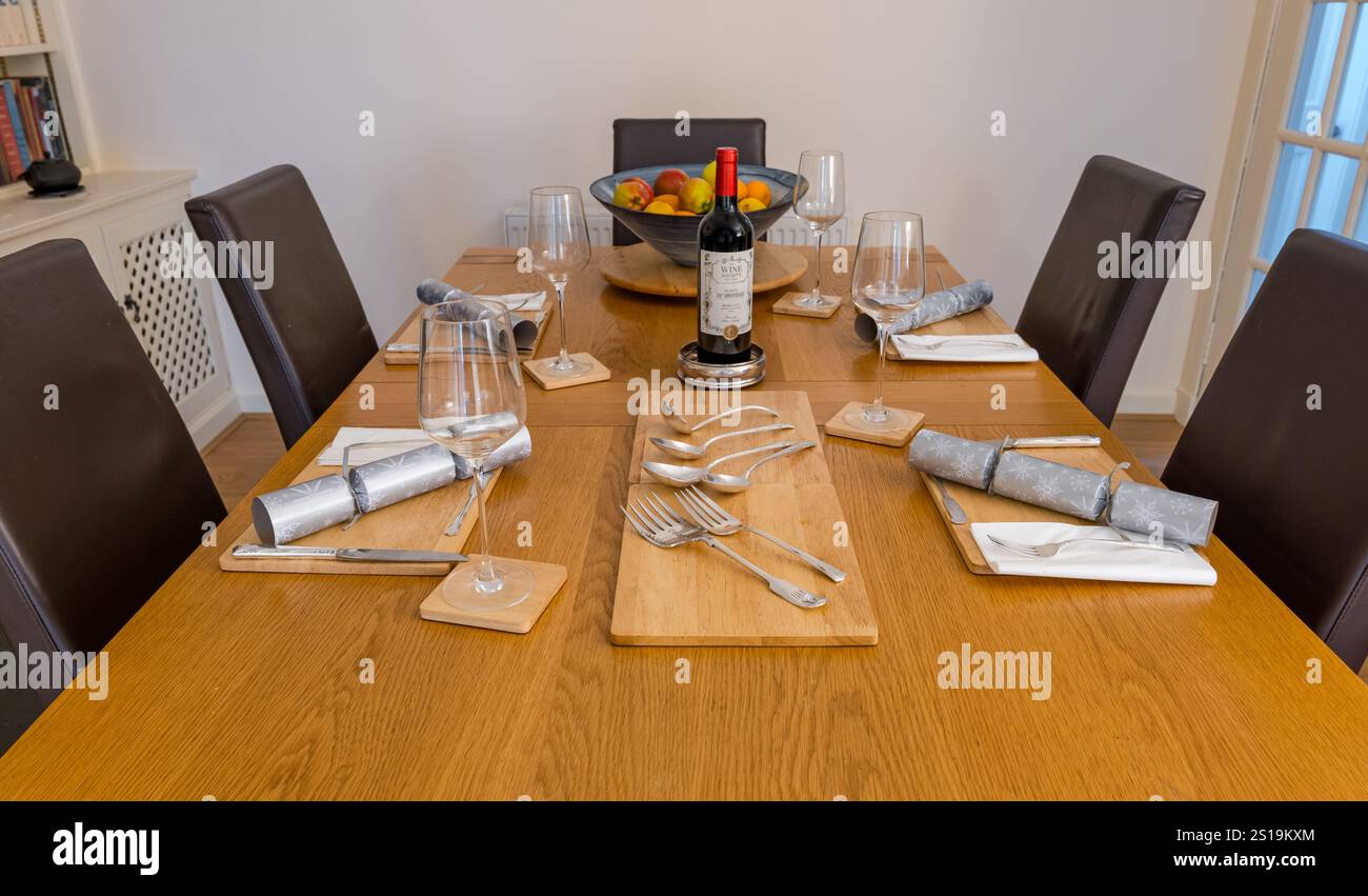 Esstisch Set für Weihnachtsessen mit Weihnachtskräckern, Flasche edlen Wein und Weingläsern, UK Stockfoto
