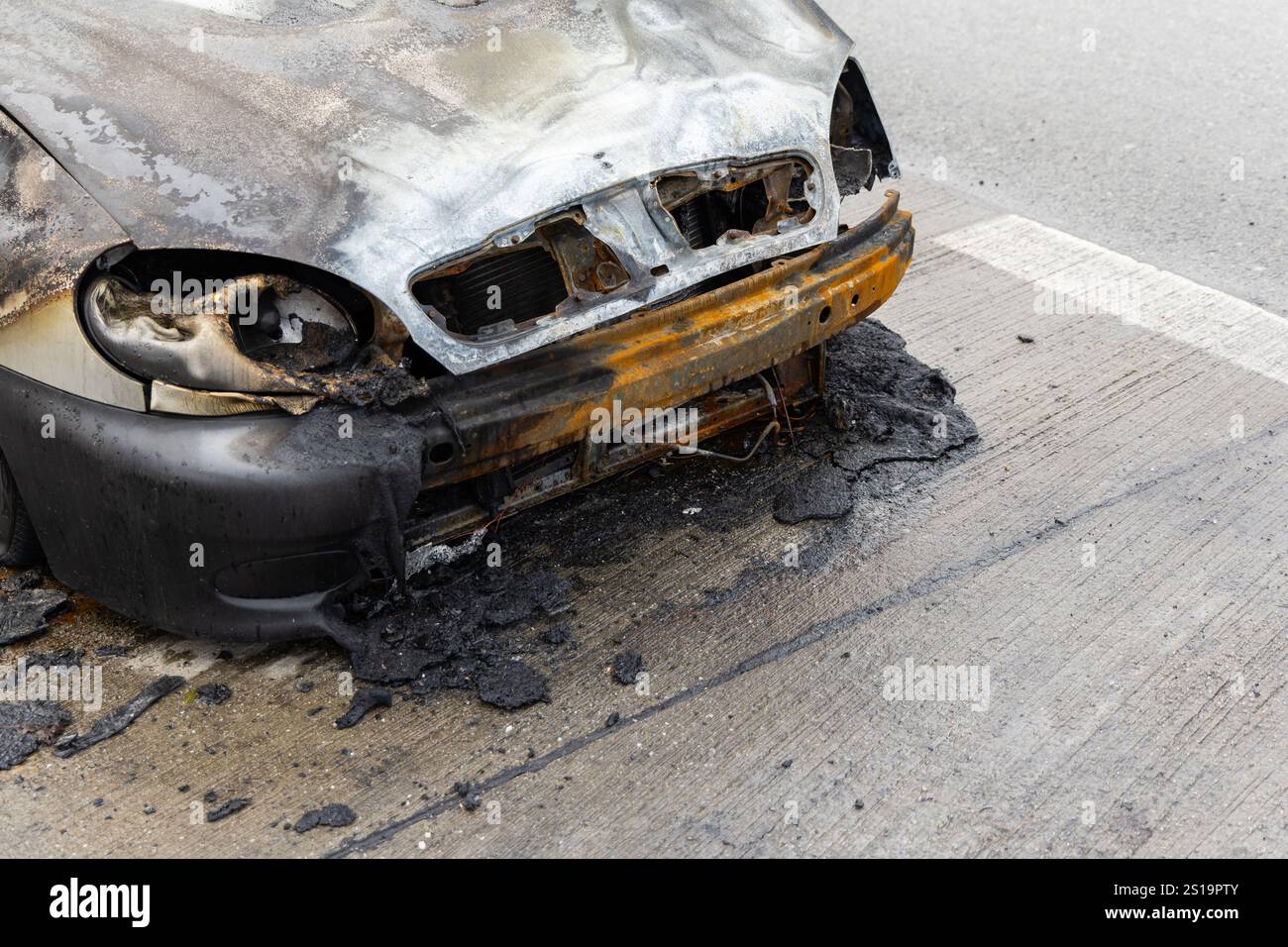 Verbrannter Pkw, der auf der Straße steht. Fahrzeug mit weitgehend ausgebranntem Innenraum. Stockfoto