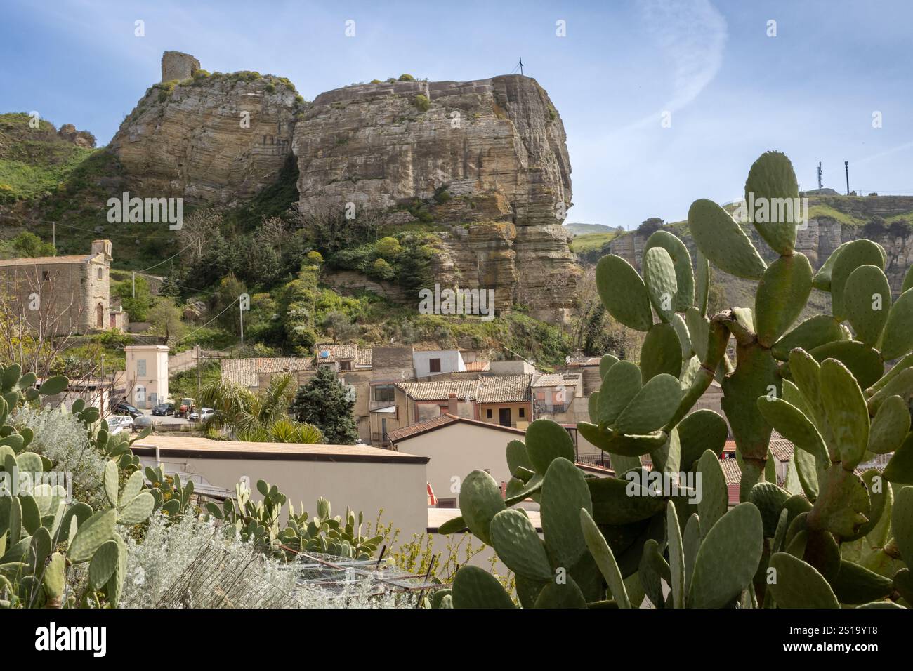 Alte Dachziegel eines Hauses im Vordergrund. Häuser der Stadt. Felsen und Berge im Hintergrund. Blauer Himmel mit hellweißen Wolken. Corleone, Sici Stockfoto