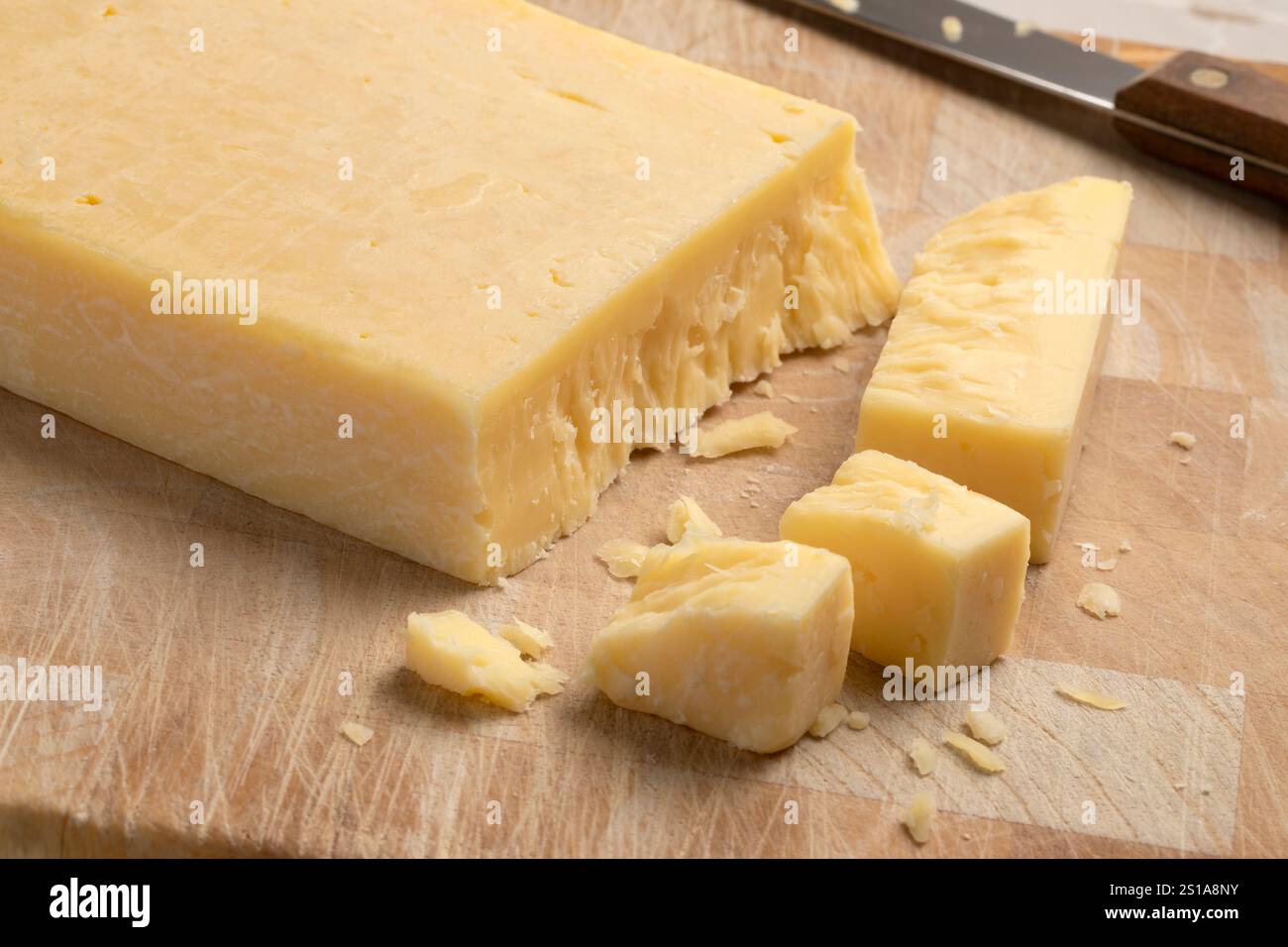 Extra reifer englischer traditioneller Cheddar-Käse und Stücke auf einem Schneidebrett Stockfoto
