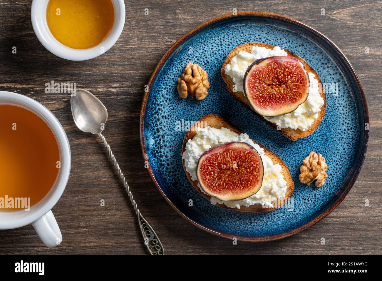 Zwei Sandwiches mit frischen Feigenscheiben, weißem Hüttenkäse, Honig und Walnüssen auf Toastbrot auf einem Teller, Blick von oben, Nahaufnahme. Gesunde Ernährung. Köstlich Stockfoto
