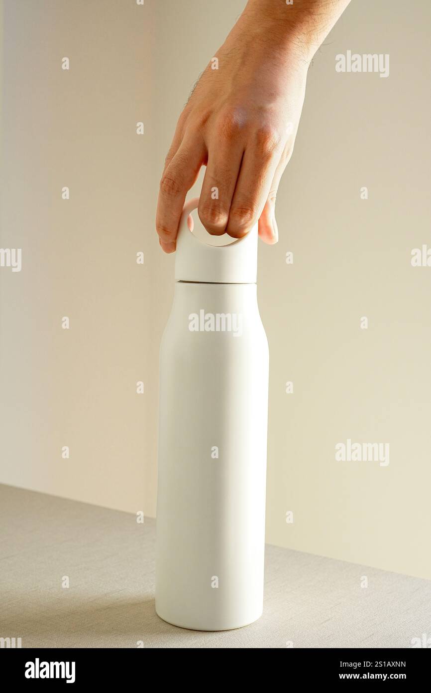 Mann, der weiße Edelstahl-Wasserflasche mit Griff auf weißem Hintergrund hält, Mockup Stockfoto